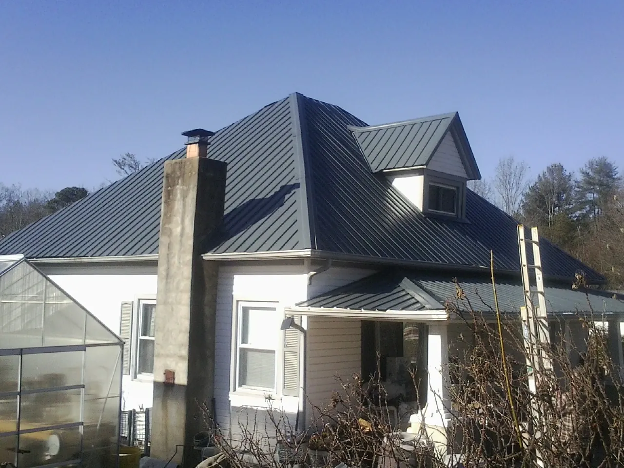 Dark blue standing seam metal roof on a white farmhouse with dormer — Slate & Tile Roof Repair by Roofing Brothers in Glen Carbon