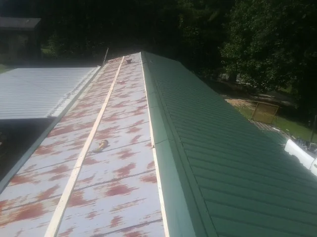Old rusted panels beside newly installed green metal roofing — Wind Damage Roof Repair by Roofing Brothers in Glen Carbon