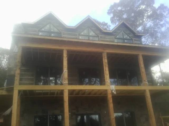 Dormers and porch framing on a large log home under construction — Roof Coating work by our crew in Glen Carbon