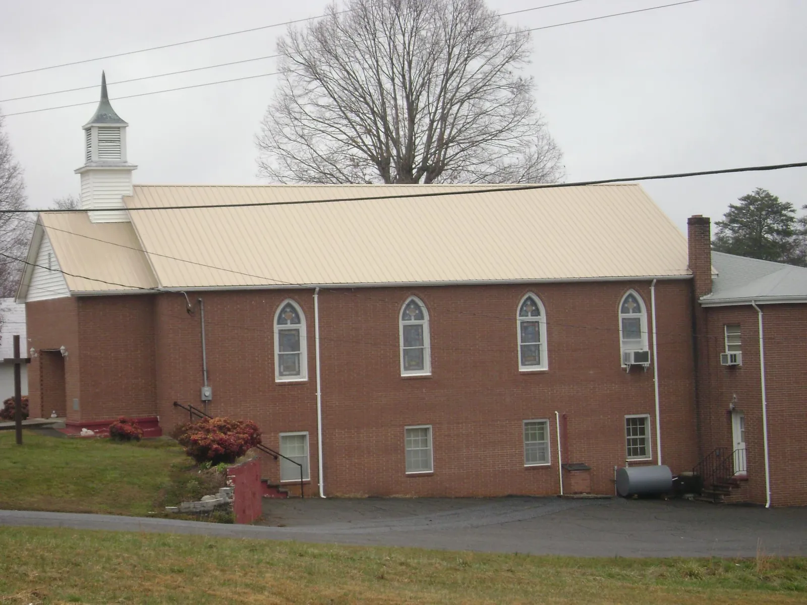 New tan metal roof on a brick church with a white steeple in Glen Carbon