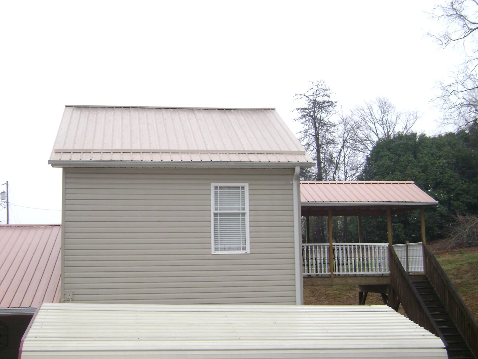 Tan metal roofs on a two story addition and attached porch, from a Roof Replacement job in Glen Carbon