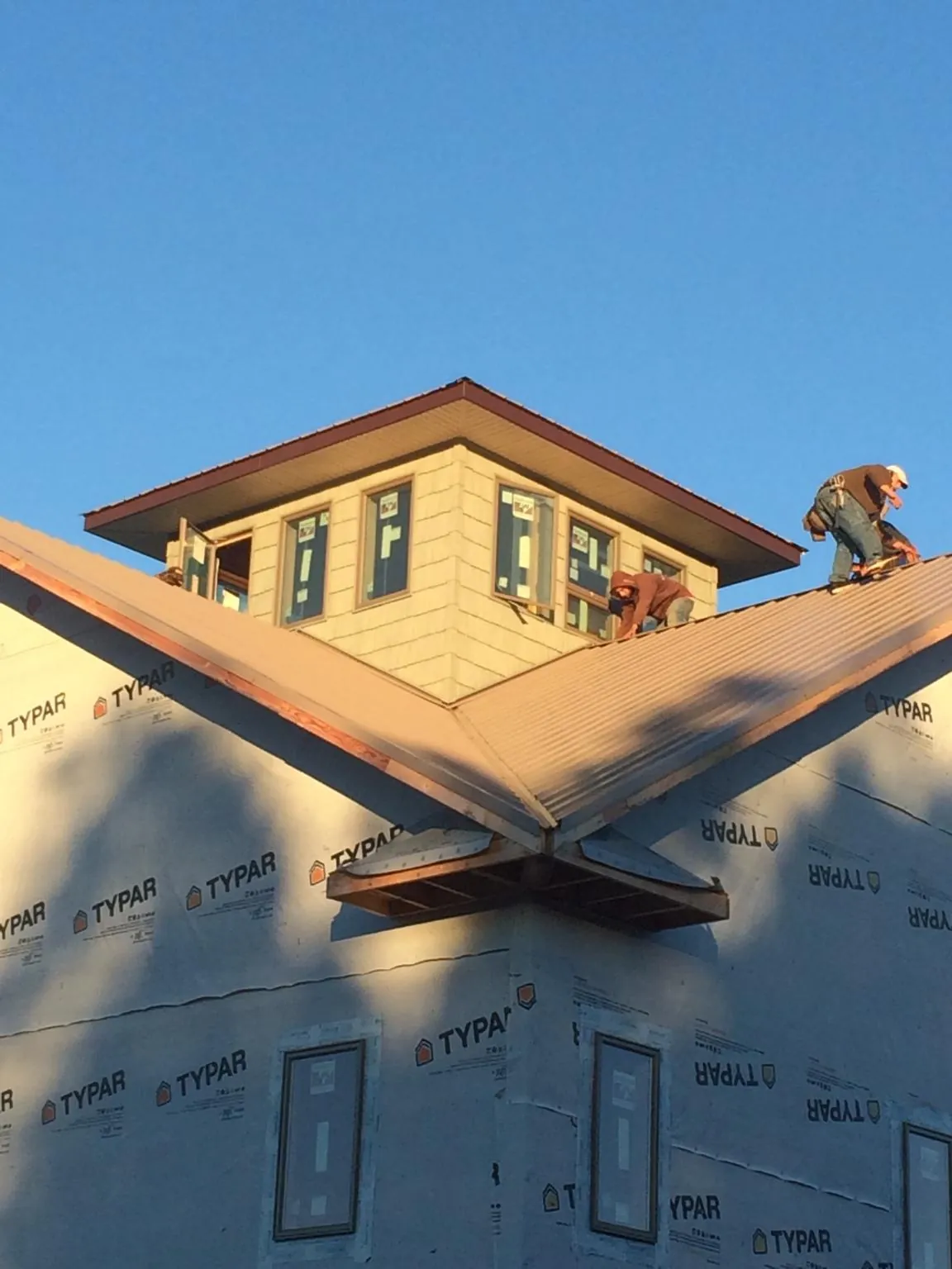 Roofers working around a rooftop cupola on a new metal roof at sunset — Roof Waterproofing in Glen Carbon by Roofing Brothers